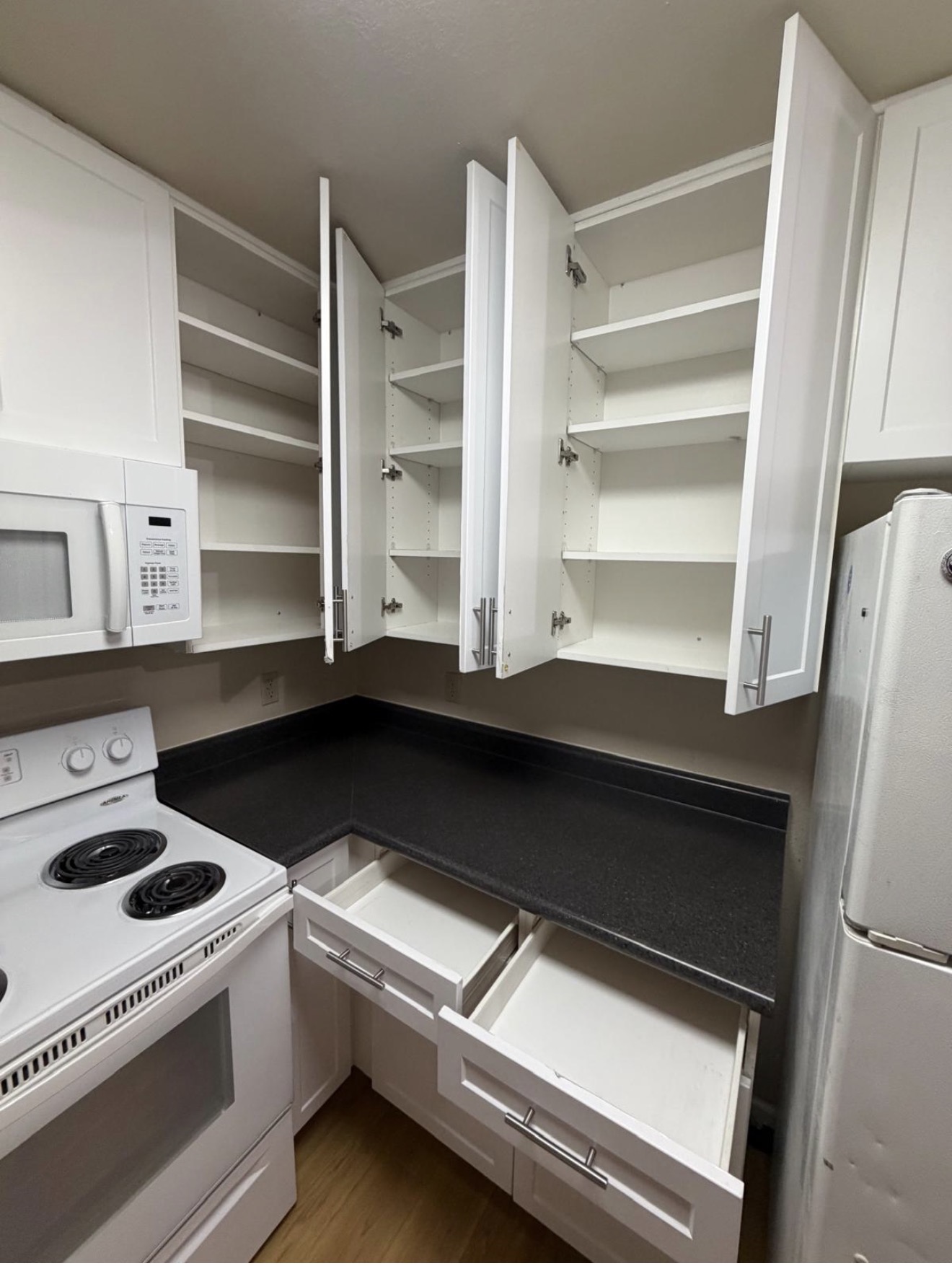 Empty kitchen cabinets and drawers wiped inside and out for move-out